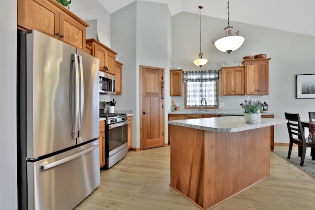 kitchen with hanging light fixtures, light countertops, high vaulted ceiling, stainless steel appliances, and light wood-type flooring