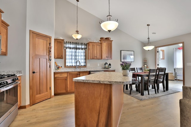 kitchen with a sink, light countertops, a center island, stainless steel appliances, and light wood-type flooring