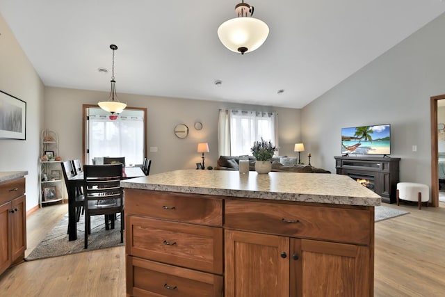 kitchen with light countertops, light wood finished floors, open floor plan, and decorative light fixtures