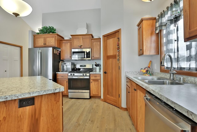 kitchen featuring a sink, light countertops, brown cabinetry, light wood-style flooring, and stainless steel appliances