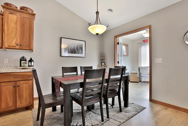 dining room with baseboards, visible vents, light wood-style flooring, and lofted ceiling