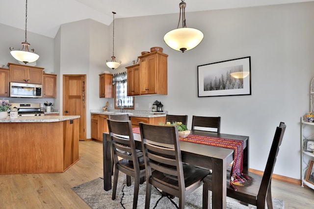dining space with high vaulted ceiling and light wood finished floors