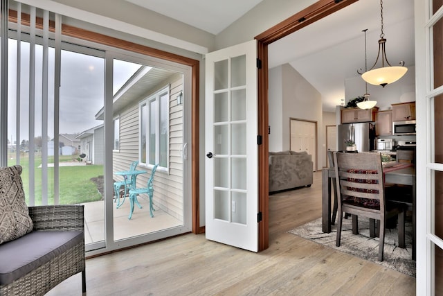 doorway to outside with lofted ceiling and light wood-style floors