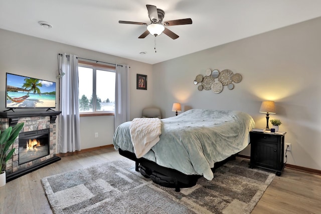 bedroom with baseboards, light wood finished floors, and a fireplace