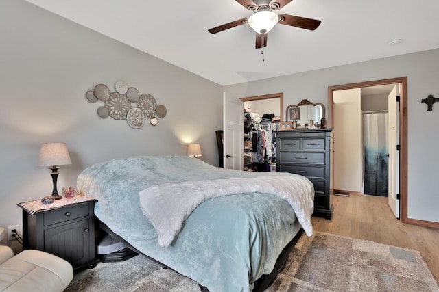 bedroom featuring a closet, a ceiling fan, light wood-style flooring, and a spacious closet