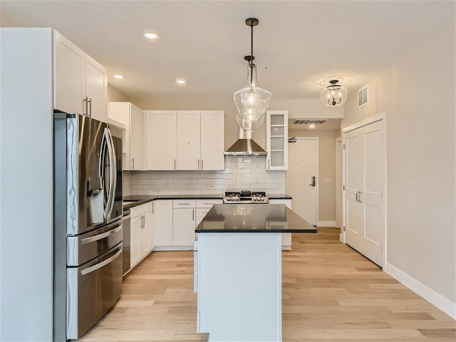 kitchen with dark countertops, stove, backsplash, stainless steel refrigerator with ice dispenser, and visible vents
