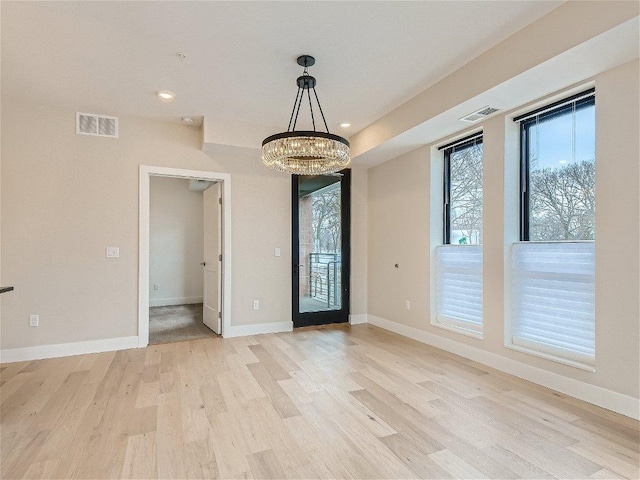 unfurnished room featuring baseboards, visible vents, an inviting chandelier, and light wood finished floors