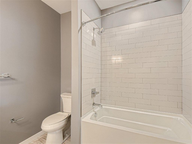 bathroom featuring baseboards, washtub / shower combination, and toilet