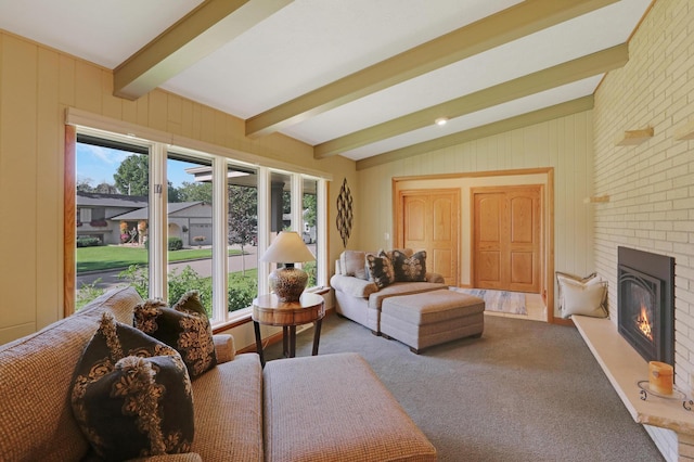 living room with carpet, lofted ceiling with beams, a brick fireplace, and a wealth of natural light