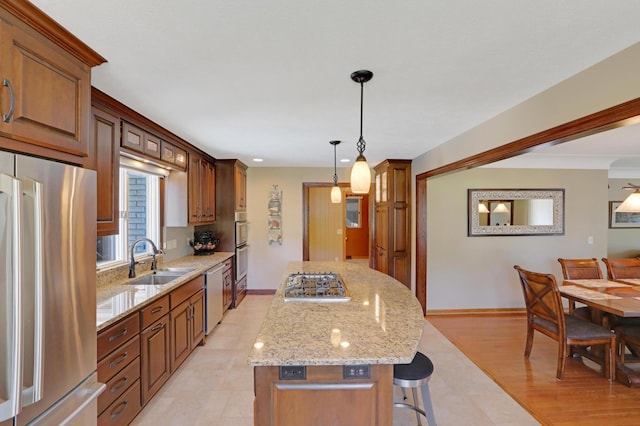 kitchen with a sink, a breakfast bar area, stainless steel appliances, baseboards, and a kitchen island