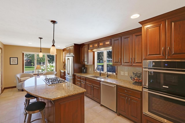 kitchen featuring a kitchen bar, a center island, light stone countertops, a sink, and stainless steel appliances