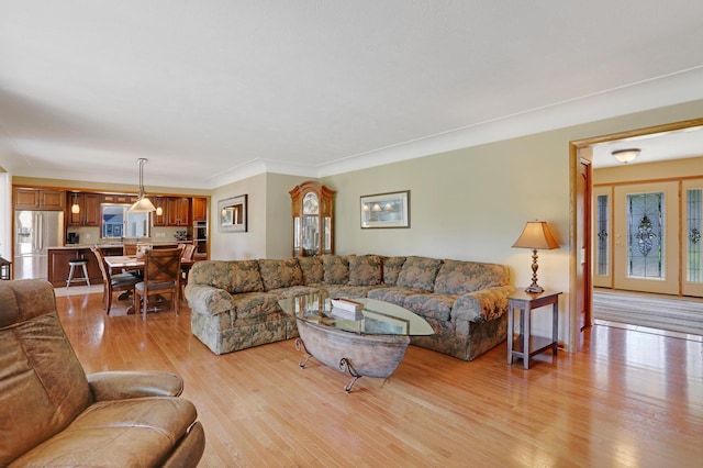 living room with crown molding, light wood-style flooring, and a wealth of natural light