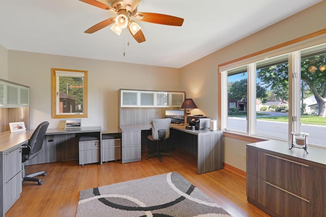 office featuring light wood-style floors, baseboards, ceiling fan, and built in desk