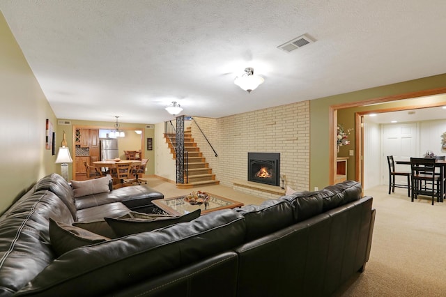 living room featuring visible vents, a brick fireplace, light carpet, stairway, and a textured ceiling