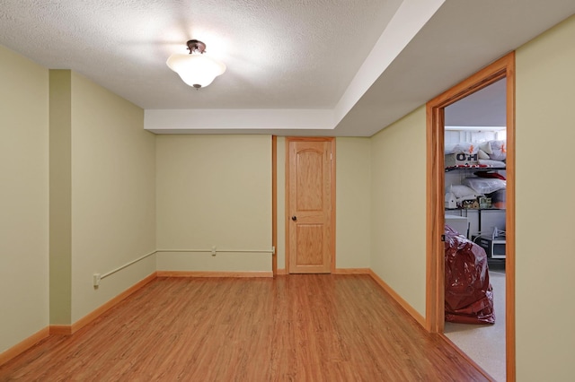 empty room featuring baseboards, a textured ceiling, and light wood-style flooring