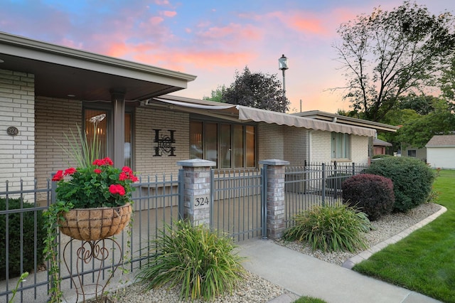 exterior space featuring a gate, covered porch, a fenced front yard, and brick siding