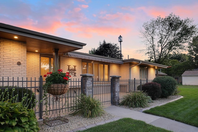 view of front of home with brick siding, a gate, a fenced front yard, and a porch