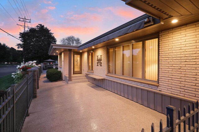 property exterior at dusk with brick siding and a patio