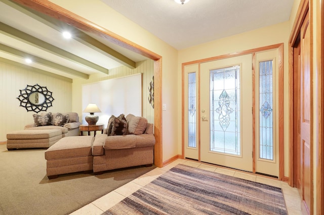 entryway featuring baseboards, beamed ceiling, and light tile patterned floors