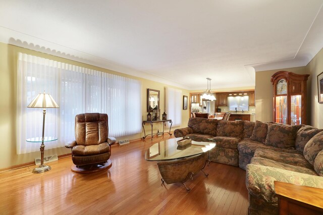 living area featuring an inviting chandelier, wood finished floors, and visible vents