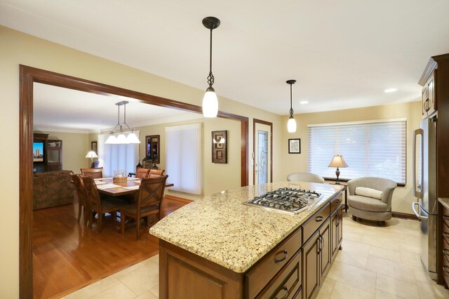 kitchen featuring light stone counters, hanging light fixtures, stainless steel appliances, light tile patterned floors, and a kitchen island