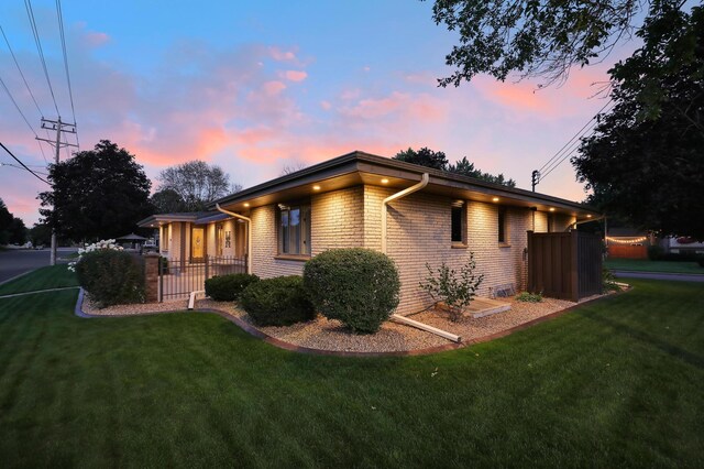 exterior space with brick siding, fence, and a front lawn