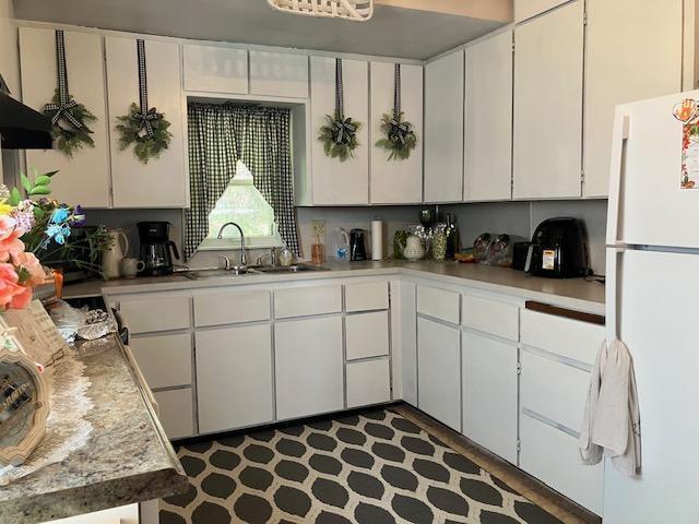 kitchen with a sink, light countertops, white cabinets, and freestanding refrigerator