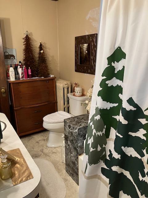bathroom featuring radiator heating unit, a shower with curtain, and toilet