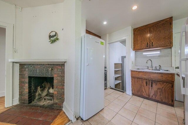 2394 Valentine Ave, Saint Paul, MN 55108 - kitchen with freestanding refrigerator, a sink, light countertops, a fireplace, and light tile patterned floors