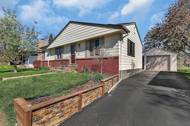 bungalow-style home featuring an outdoor structure, a garage, a front lawn, brick siding, and driveway