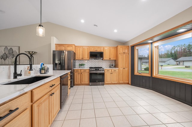 kitchen featuring a sink, appliances with stainless steel finishes, backsplash, and vaulted ceiling