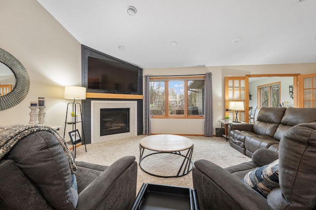 carpeted living area featuring baseboards, vaulted ceiling, and a fireplace