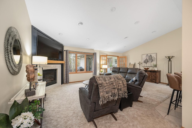 living area featuring baseboards, light colored carpet, a glass covered fireplace, and lofted ceiling