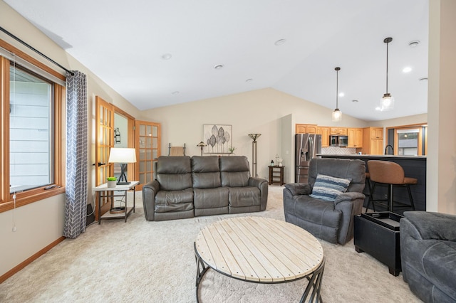 living area with baseboards, vaulted ceiling, and light colored carpet