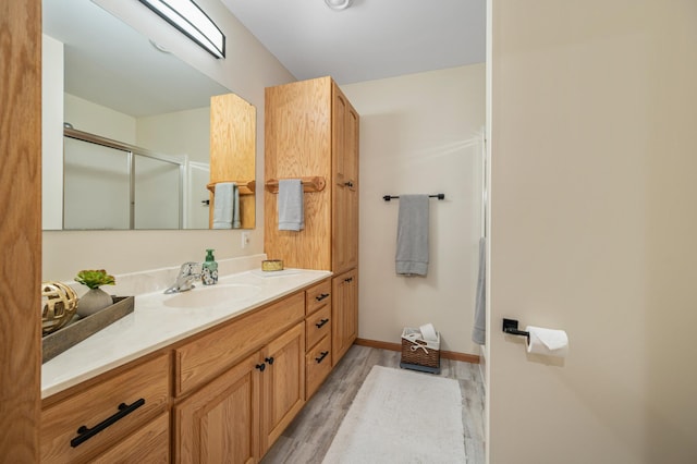 full bath featuring vanity, baseboards, wood finished floors, and a shower stall