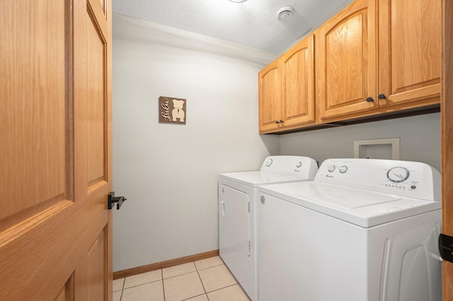 laundry room with washing machine and dryer, baseboards, a textured ceiling, cabinet space, and light tile patterned floors