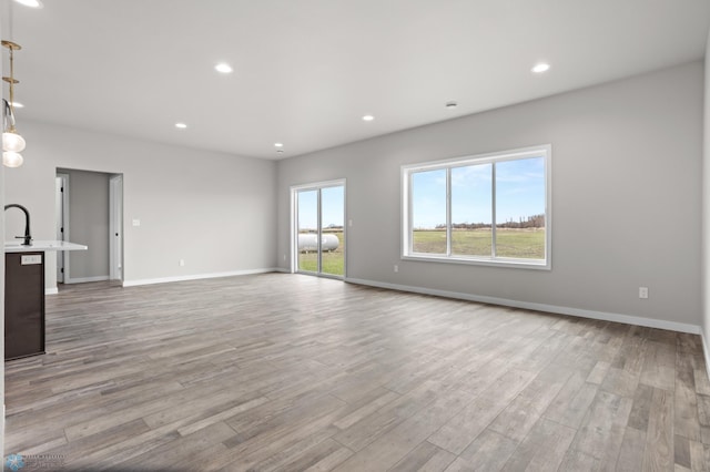 unfurnished living room featuring recessed lighting, baseboards, and wood finished floors