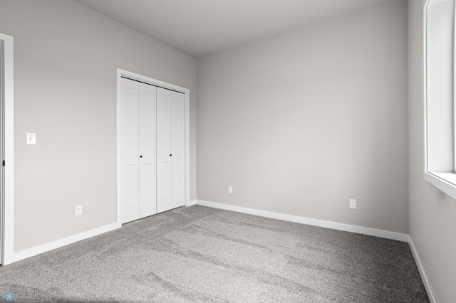 unfurnished bedroom featuring carpet floors, baseboards, and a closet