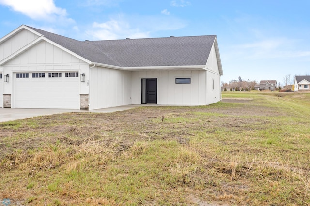view of front of property with an attached garage, a shingled roof, board and batten siding, and a front yard