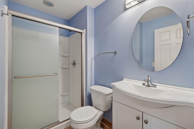 full bathroom with vanity, toilet, a textured ceiling, and a stall shower
