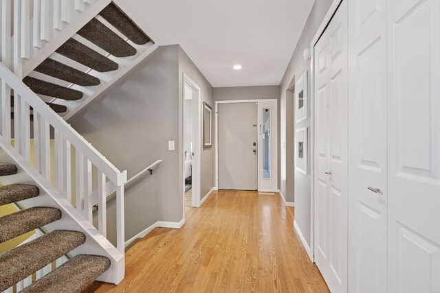 corridor featuring baseboards, recessed lighting, light wood-style flooring, and stairs