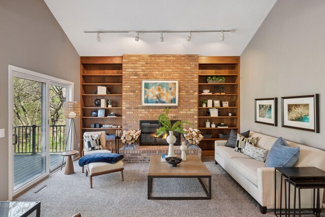 living area featuring track lighting, carpet flooring, built in features, and a fireplace