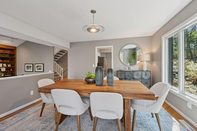dining room with stairway, baseboards, wood finished floors, and a healthy amount of sunlight