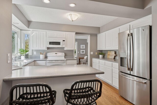 kitchen featuring white cabinetry, a peninsula, and white appliances