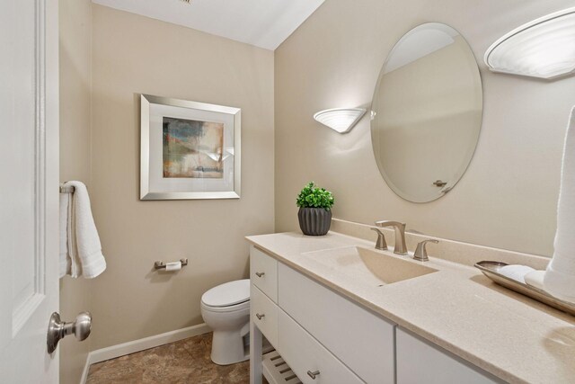 bathroom featuring toilet, baseboards, and vanity