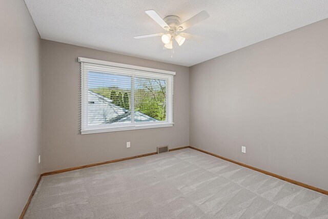 spare room featuring a ceiling fan, visible vents, and light carpet