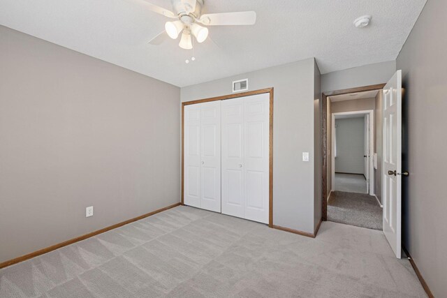 unfurnished bedroom with a closet, baseboards, light colored carpet, and visible vents