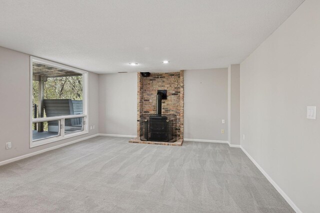unfurnished living room with carpet floors, recessed lighting, baseboards, and a wood stove