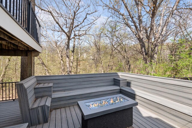deck featuring a wooded view and a fire pit