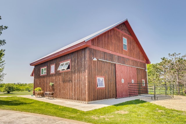 view of side of property featuring fence, an outbuilding, a lawn, and a barn
